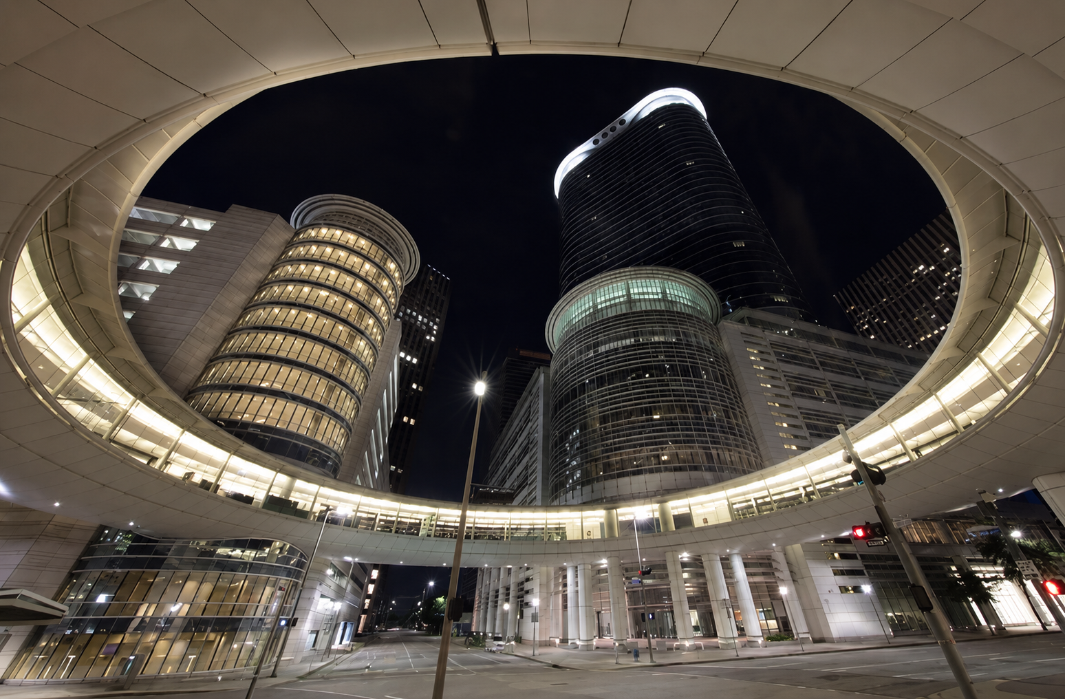 Modern Houston skyscraper framed by a circular pedestrian bridge at night